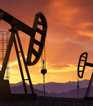 Oil pumps extracting crude at sunset. Oil drill and pump jack in oilfield.